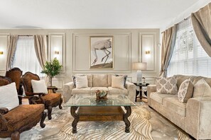 A living room with a sofa set, a coffee table, and a framed artwork on the wall. - 6BR Near Disney, Pool, Games and Themed Rooms (Kissimmee)