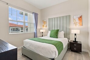 A modern bedroom with a bed, nightstands, a desk, and artwork on the walls. - Spacious 3BR Condo, Perfect Orlando Home Base (Orlando)