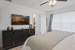 A bedroom with a bed, a dresser, a television on the wall, and a ceiling fan. - Chic 6br, Pool, Themed Rooms, Near Disney (Kissimmee)