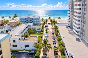 A coastal residential area with buildings, a parking lot, and a view of the ocean. - Steps to Hollywood Beach - Modern 1BR Retreat (Hollywood)