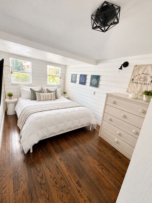 A bedroom with a bed, dresser, and wall decor. - Historic Home: Walk to Downtown, Jays & Waterfront (Dunedin)