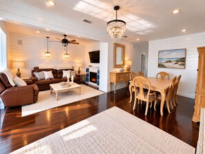 A spacious living room with a fireplace, a dining area with wooden furniture, and a ceiling fan. - Historic Home: Walk to Downtown, Jays & Waterfront (Dunedin)