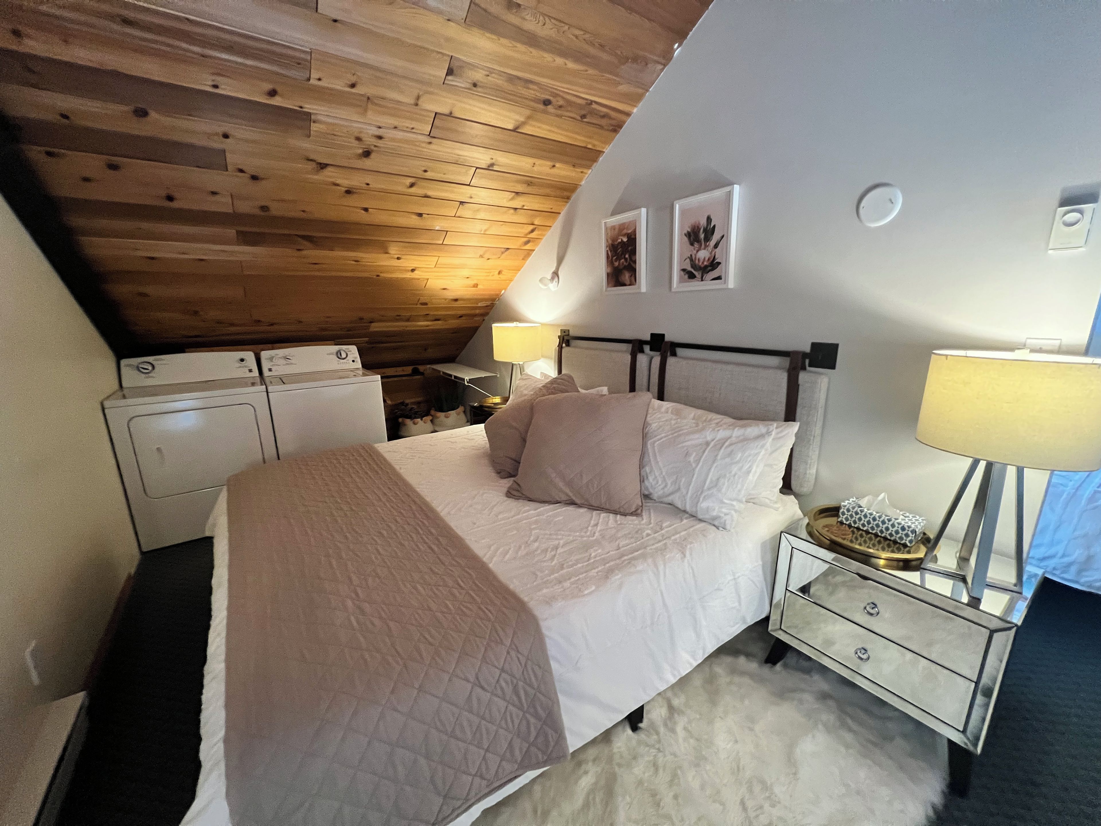Une chambre à coucher avec un lit, des tables de chevet, une lampe et un lave-linge.