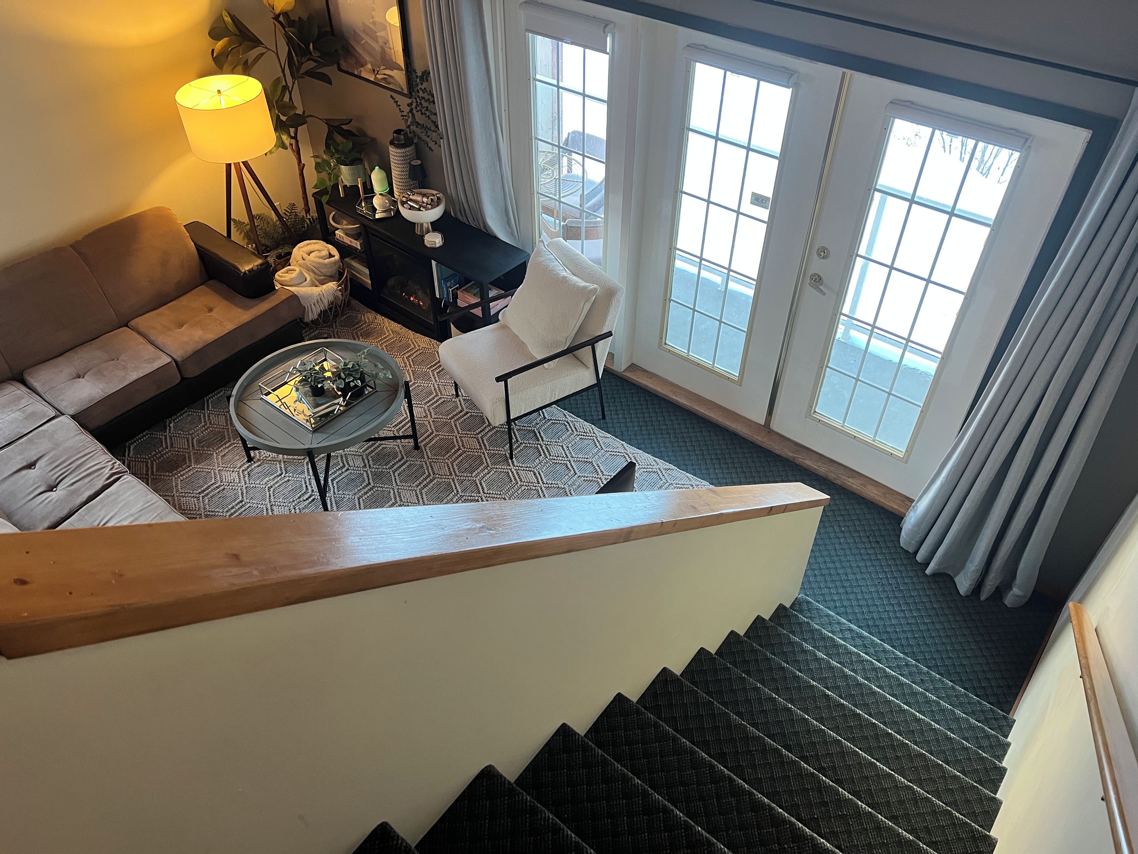 Eine Treppe führt zu einem Wohnbereich mit einer Couch, einem Couchtisch und einem Sessel.