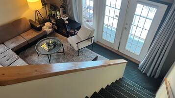 Eine Treppe führt zu einem Wohnbereich mit einer Couch, einem Couchtisch und einem Sessel.