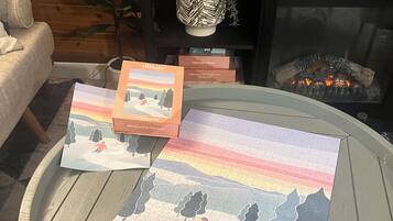 Ein runder Glastisch mit einem Puzzle, einem Buch mit dem Titel 'Stunning Iceland' und einem dekorativen Gegenstand auf einer Holzoberfläche.