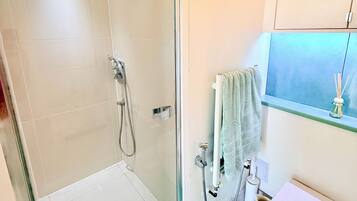 A bathroom with a glass-enclosed shower, a toilet, and a sink.