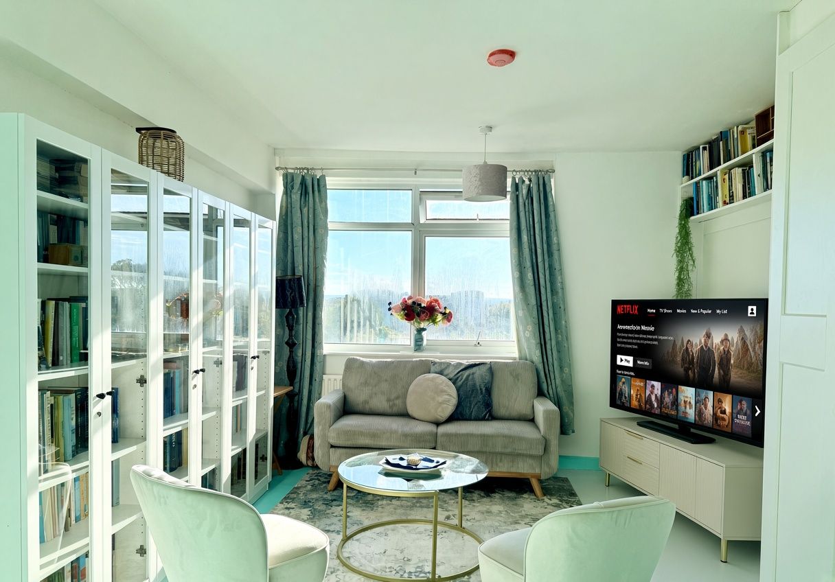 A living room with a sofa, a coffee table, a bookshelf, and a television.