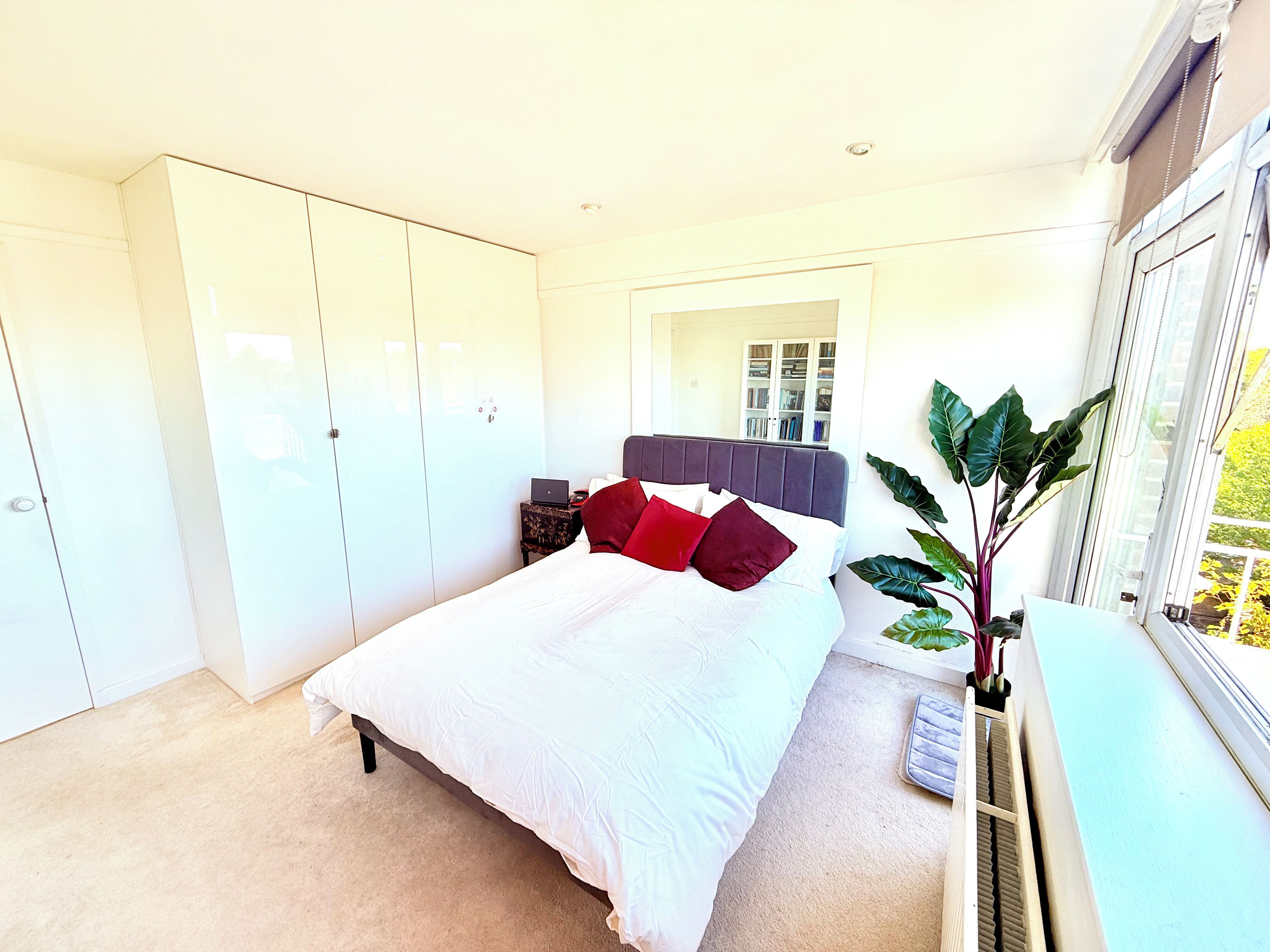 A bedroom with a bed, wardrobe, bedside table, and a window with a view.