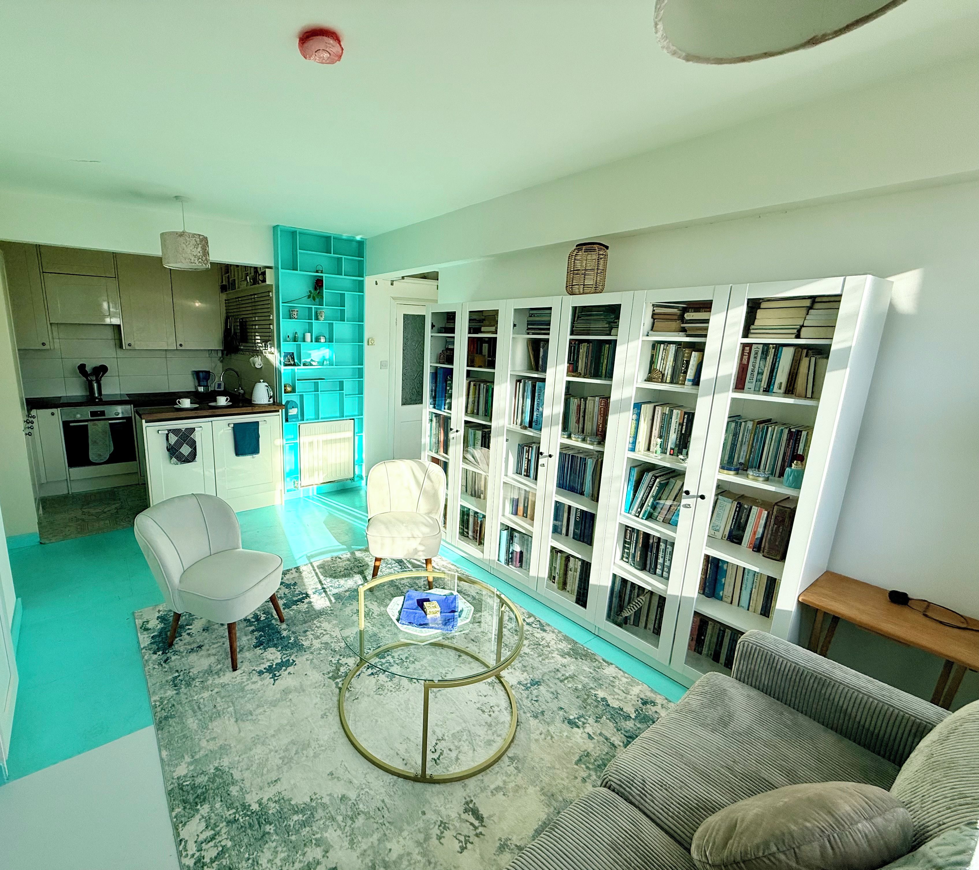 Ein Wohnzimmer mit einer Couch, einem Couchtisch und einem Bücherregal voller Bücher.