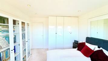 A bedroom with a bed, a wardrobe, and a bookshelf.
