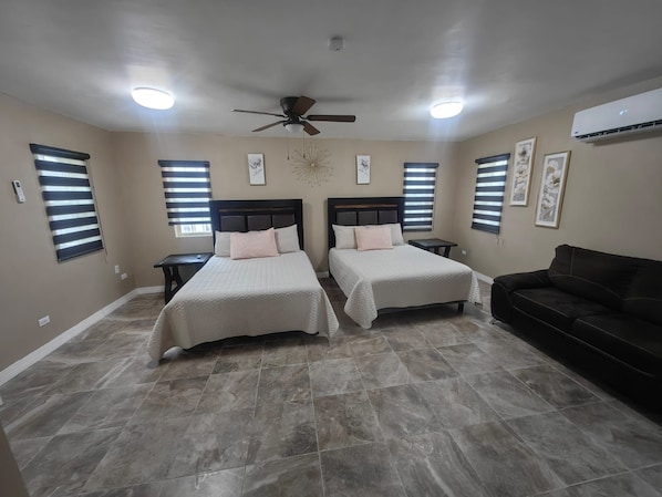 A bedroom with two beds, a ceiling fan, and an air conditioning unit.