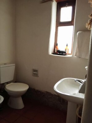 Un baño pequeño con inodoro, lavabo y ventana.
