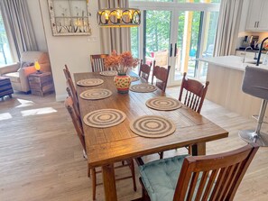 Zona pranzo con tavolo in legno, sottopiatti intrecciati e sedie.