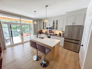 A modern kitchen with a central island, stainless steel appliances, and a sliding glass door leading to an outdoor area.