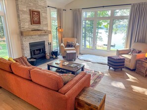 A living room with a fireplace, a sofa, a chair, and a view of the outdoors.