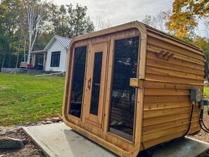 Una struttura in legno con un'ampia finestra e una porta, posizionata su una piattaforma in cemento.