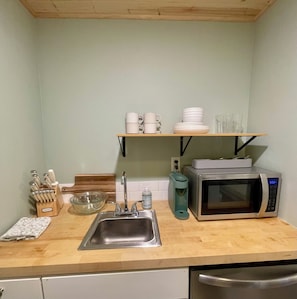 Una cocina con un lavamanos de acero inoxidable, un microondas y una cafetera en la encimera.