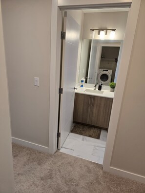 Et badeværelse med toilet, vask, spejl og en vaskemaskine.