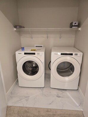 Dues rentadora de càrrega frontal Whirlpool blanques en una cambra de bugaderia amb sòl de marbre i una catifa beix.
