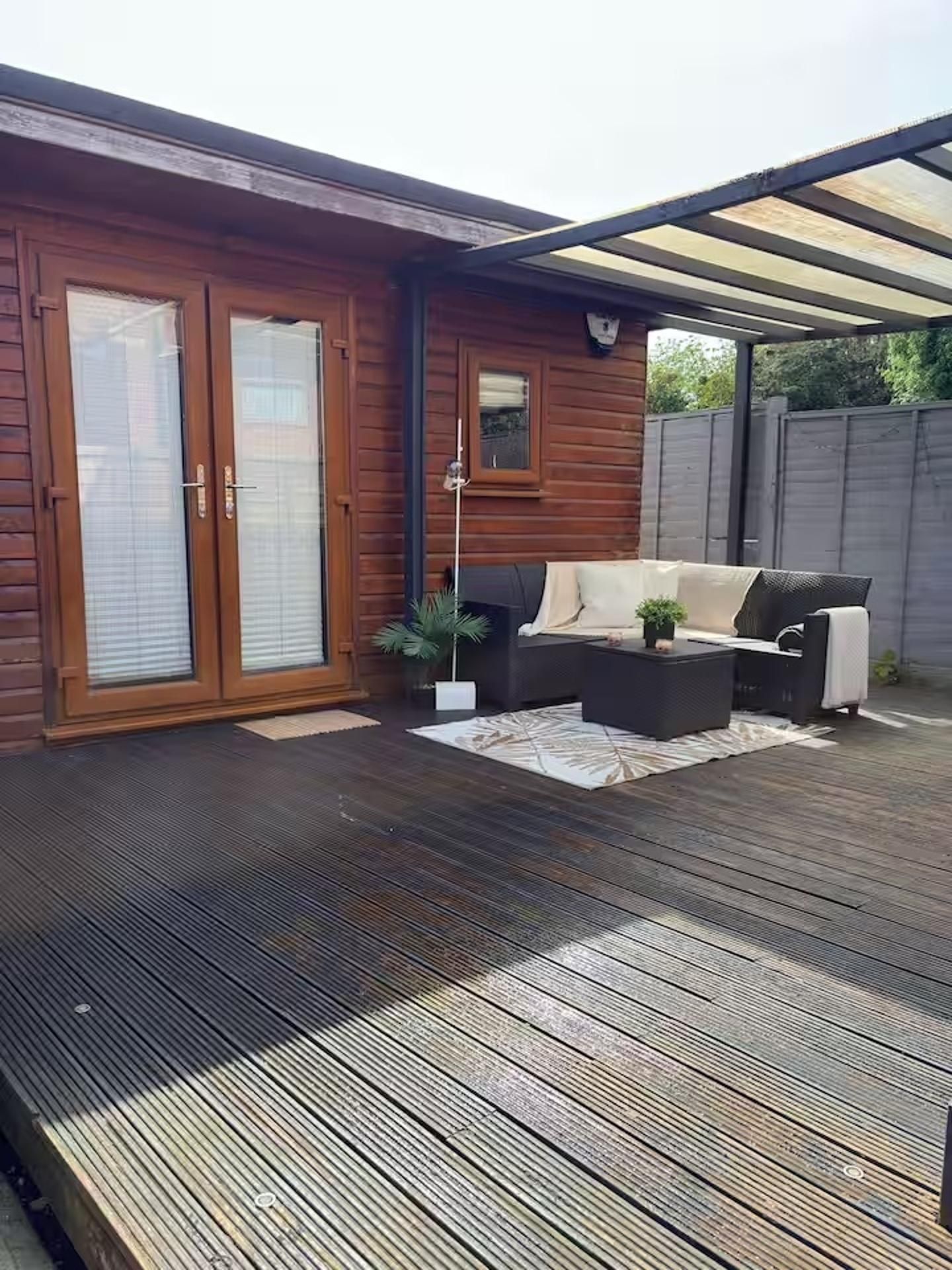 A wooden deck with a sofa and coffee table, a covered patio area, and a sliding glass door.