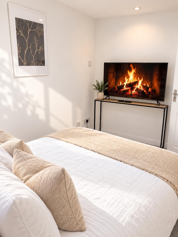 A bedroom with a bed, a fireplace, and a framed picture on the wall.