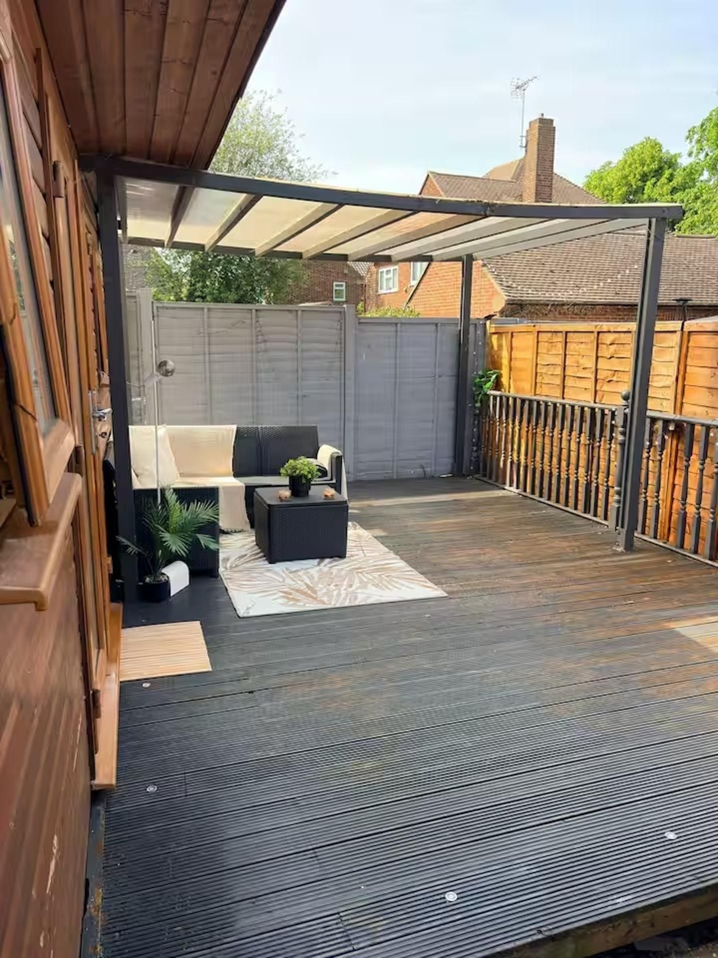Un patio couvert aménagé avec des sièges et une terrasse en bois.