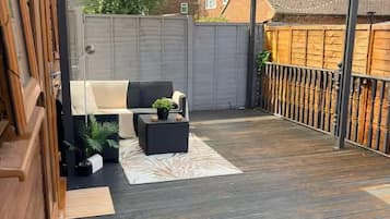 Un patio couvert aménagé avec des sièges et une terrasse en bois.