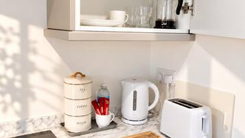 Een keuken met een inbouwfornuis, een broodrooster, een waterkoker en een koffiezetapparaat.