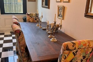 A dining table with ornate candle holders, patterned upholstery, and framed artwork on the walls. - Charming uptown New Orleans retreat (New Orleans)