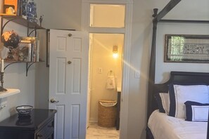 Una camera da letto con un letto, un comodino, una lampada e uno scaffale con libri e oggetti decorativi.