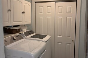 A laundry area with two washing machines and a closed door. - Charming uptown New Orleans retreat (New Orleans)