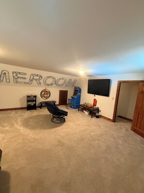 Una habitación con dardos, una televisión montada en la pared y un ventilador de techo.
