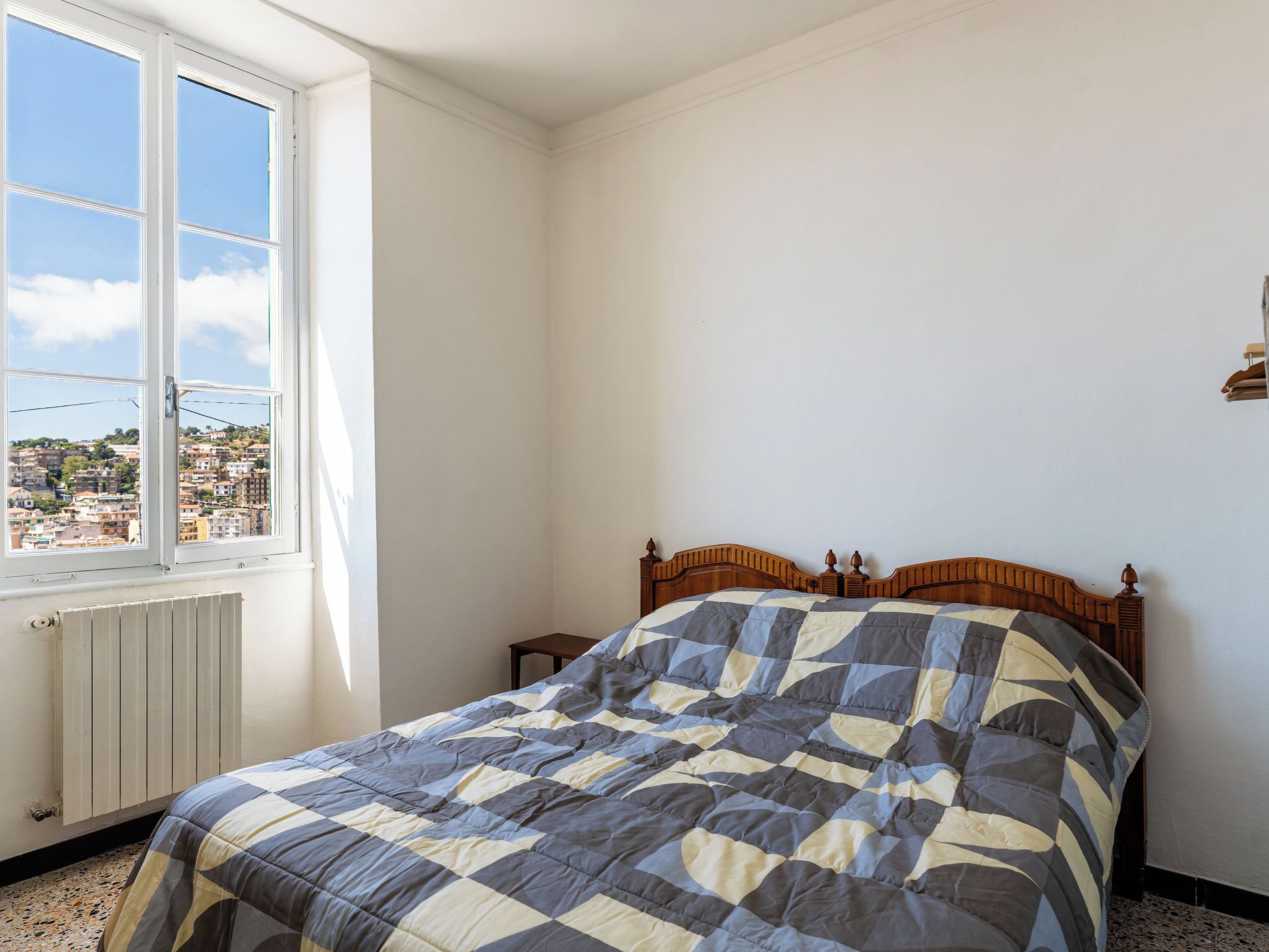 A bedroom with a bed, a window, and a radiator.