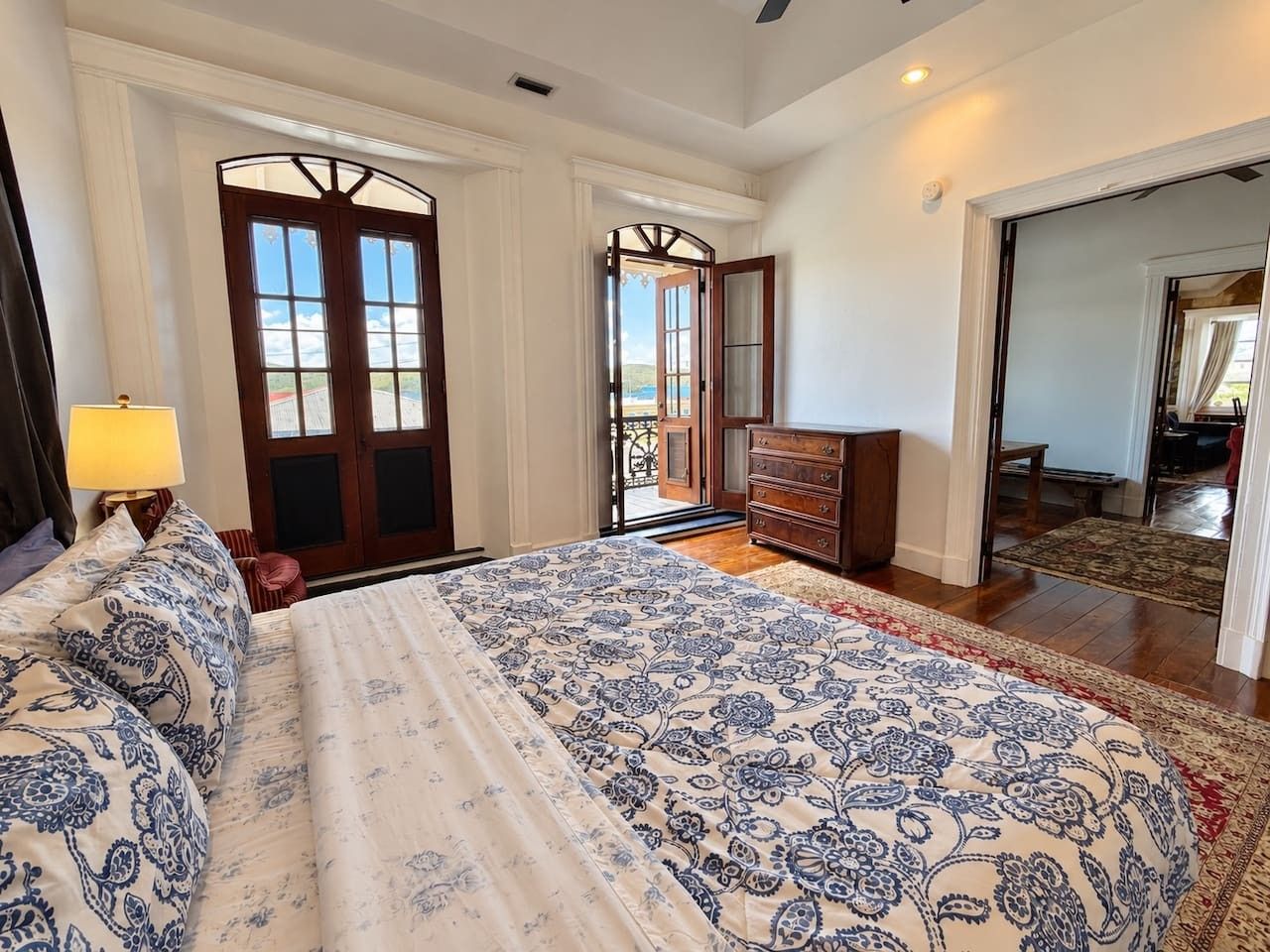 Une chambre avec un grand lit, une commode et une vue sur l’extérieur par une porte.