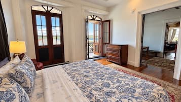 Une chambre avec un grand lit, une commode et une vue sur l’extérieur par une porte.