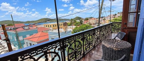 A balcony with wicker furniture and a view of a coastal town.