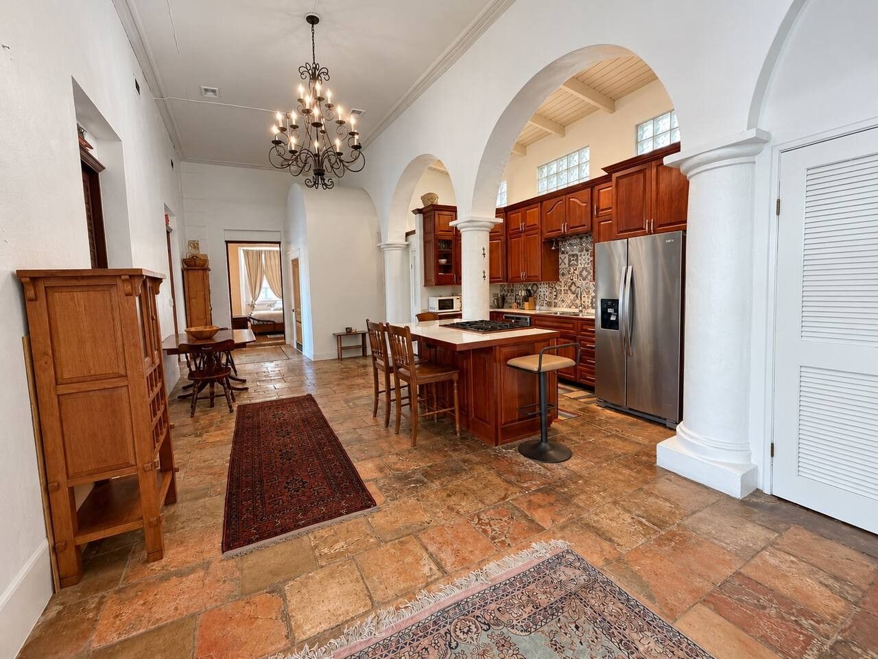 A spacious kitchen with a central island, wooden cabinets, and a stainless steel refrigerator.