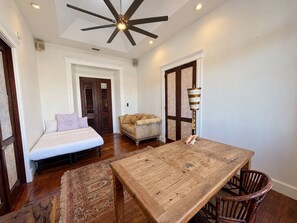 Ein Zimmer mit einem Holztisch, einer Couch und einem Deckenventilator.