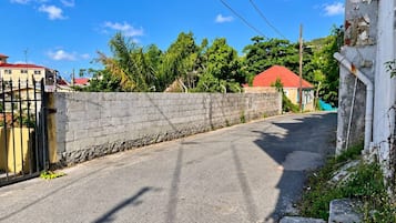 A narrow street with a stone wall on one side and a gated entrance on the other.