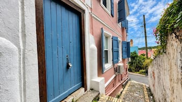 A narrow alleyway with a pink building, a blue door, and a white wall.