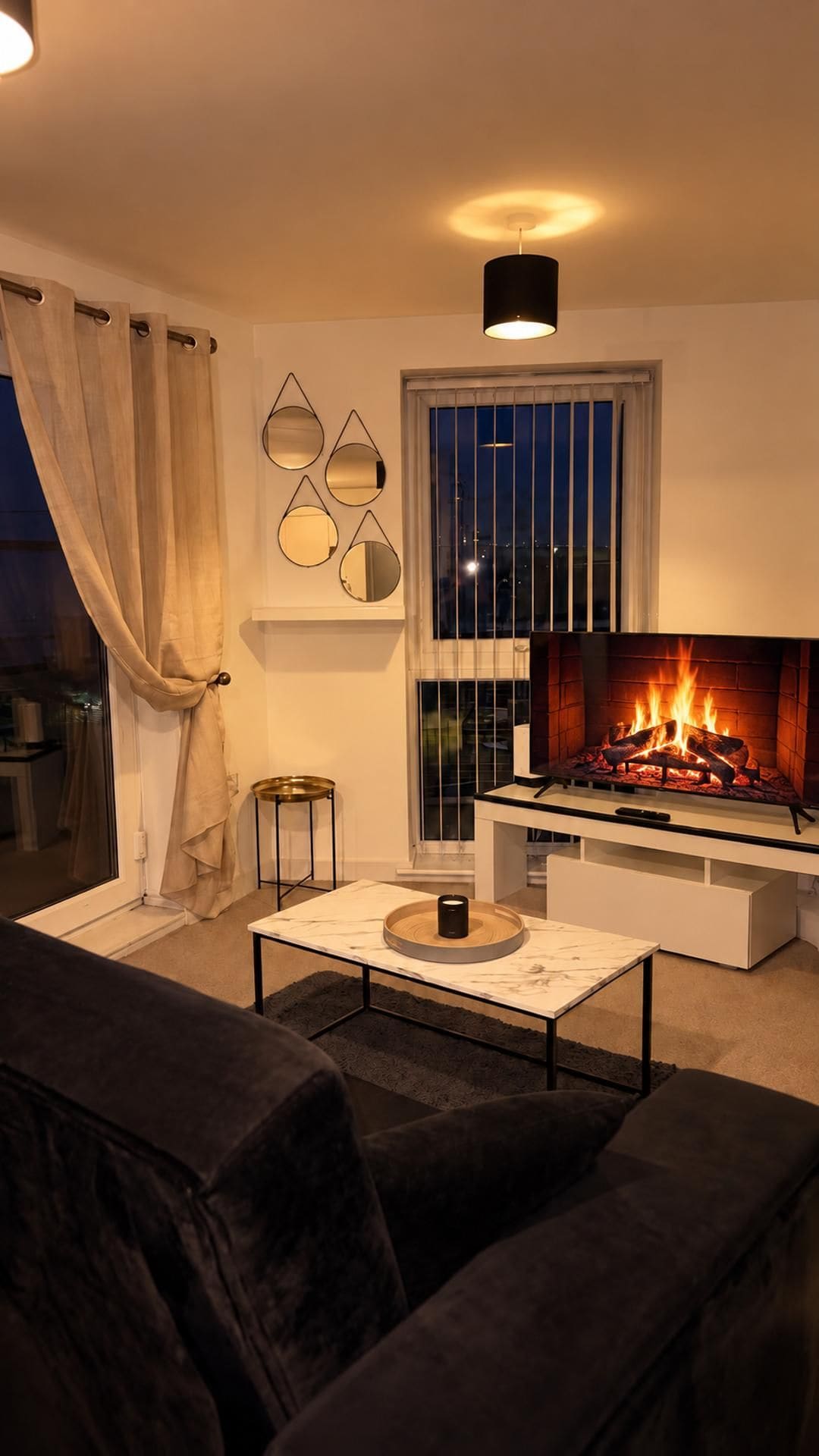 Una sala de estar con chimenea, una mesa de centro, un sofá y una ventana con cortinas.