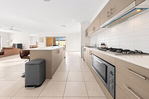 Una cocina moderna con una isla central, electrodomésticos de acero inoxidable y vistas al área de comedor.
