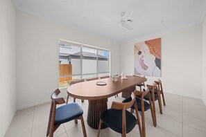 Un comedor moderno con una mesa redonda, sillas de madera y un ventilador de techo.