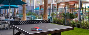 An outdoor table tennis setup with a net, two paddles, and a ball. - Resort 1 bedroom in Anaheim for National Association of Music Merchants - NAMN (Anaheim)