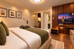 Ein modernes Hotelzimmer mit einem großen Bett, einem Fernseher und Blick auf die beleuchtete Stadt bei Nacht.