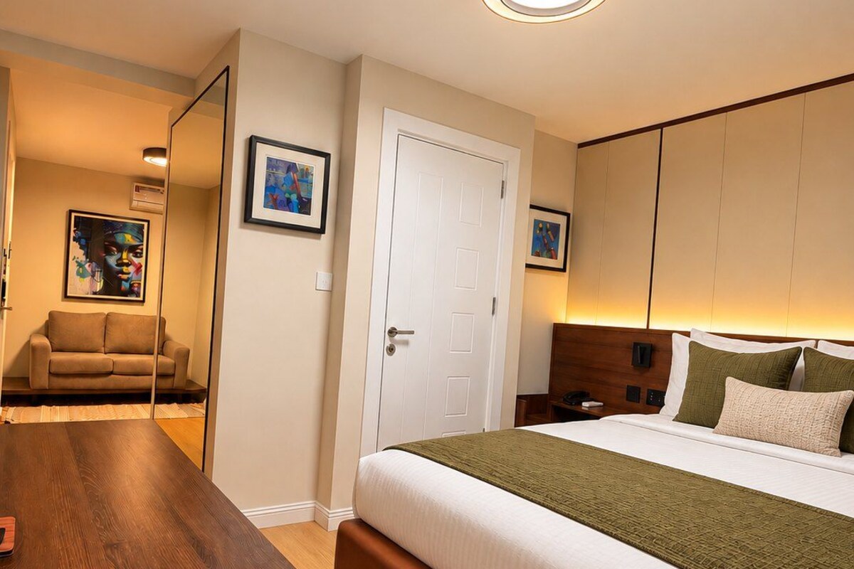 Ein Hotelzimmer mit einem Bett, einem Nachttisch, einer Couch und einem Spiegel.