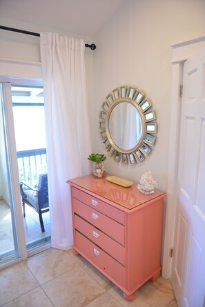 A pink dresser with drawers, a mirror with a gold frame, a small plant, and a decorative item on top. - Luxury Island Escape 3BR, Panoramic Views, AC, Pool, Free Concierge, & Generator (St Thomas)