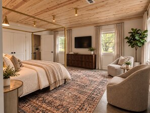 A bedroom with a bed, a dresser, a TV, a chair, and a large window. - The Guesthaus- A Cozy Wooded Retreat in Murfreesboro (Murfreesboro)