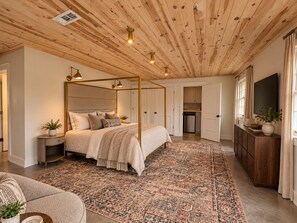 A bedroom with a four-poster bed, a large patterned rug, and a wooden ceiling. - The Guesthaus- A Cozy Wooded Retreat in Murfreesboro (Murfreesboro)